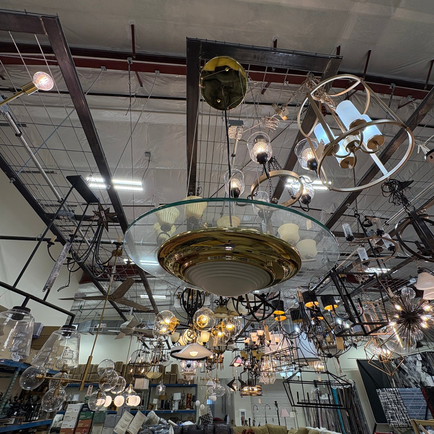 GDM Habitat for Humanity ReStore showroom featuring a large brass and glass pendant light fixture among many lamps