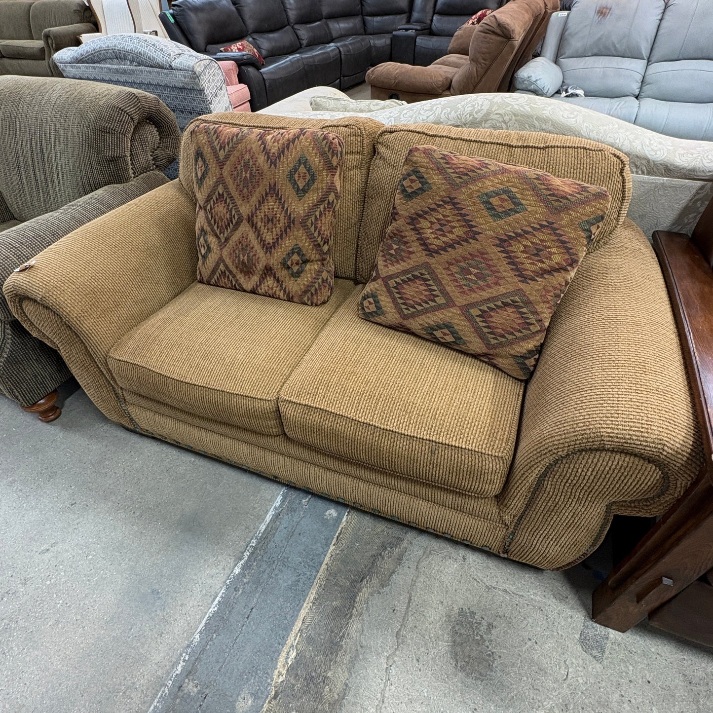 GDM Habitat for Humanity ReStore tan chenille loveseat with two patterned diamond-print throw pillows.