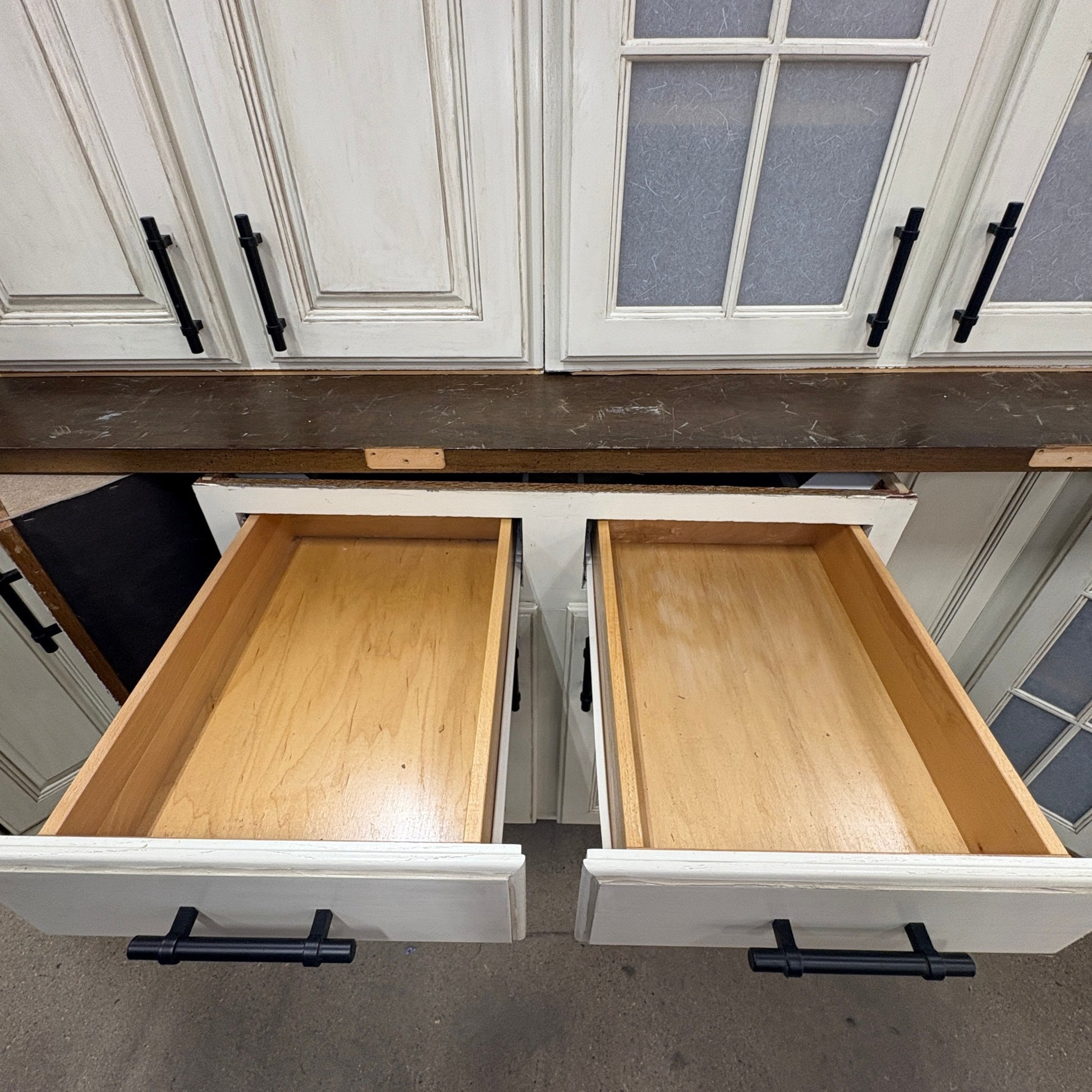 GDM Habitat for Humanity ReStore antique white kitchen cabinets with open wooden drawers and black metal handles