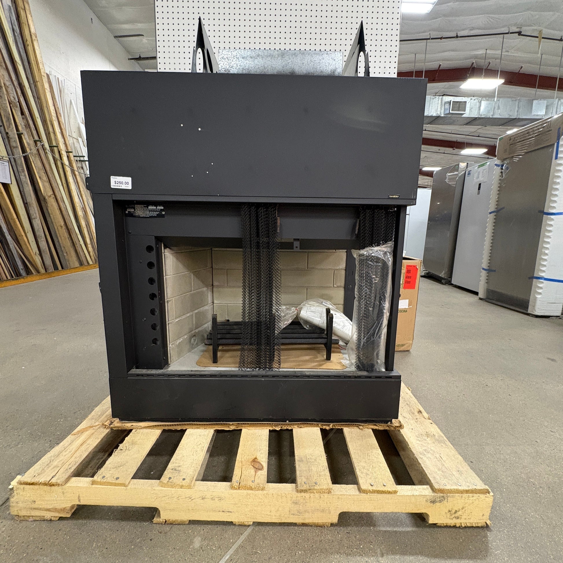 GDM Habitat for Humanity ReStore black metal fireplace insert with brick interior on a wooden shipping pallet