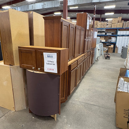 GDM Habitat for Humanity ReStore 13-piece brown wooden kitchen cabinet set displayed in a warehouse showroom.