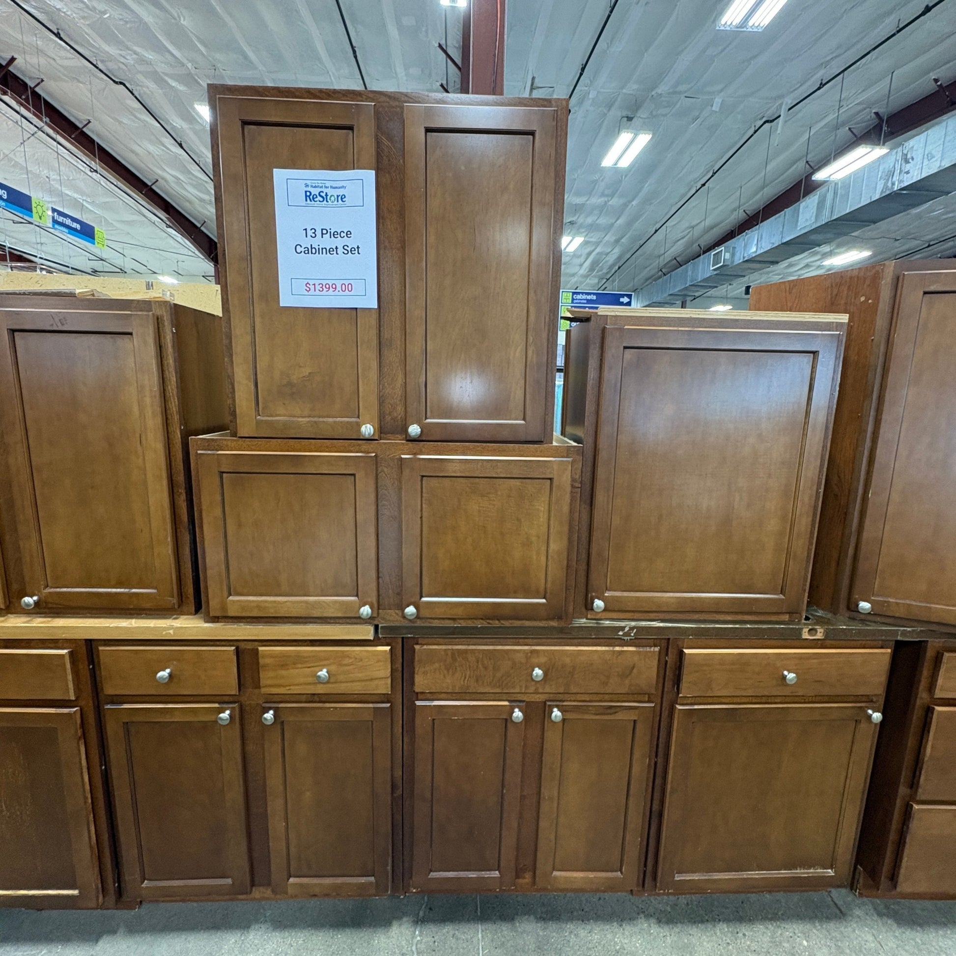 GDM Habitat for Humanity ReStore 13-piece brown wooden kitchen cabinet set with shaker style doors and silver knobs.