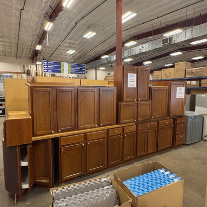 GDM Habitat for Humanity ReStore 13 piece brown wooden kitchen cabinet set displayed in a warehouse showroom