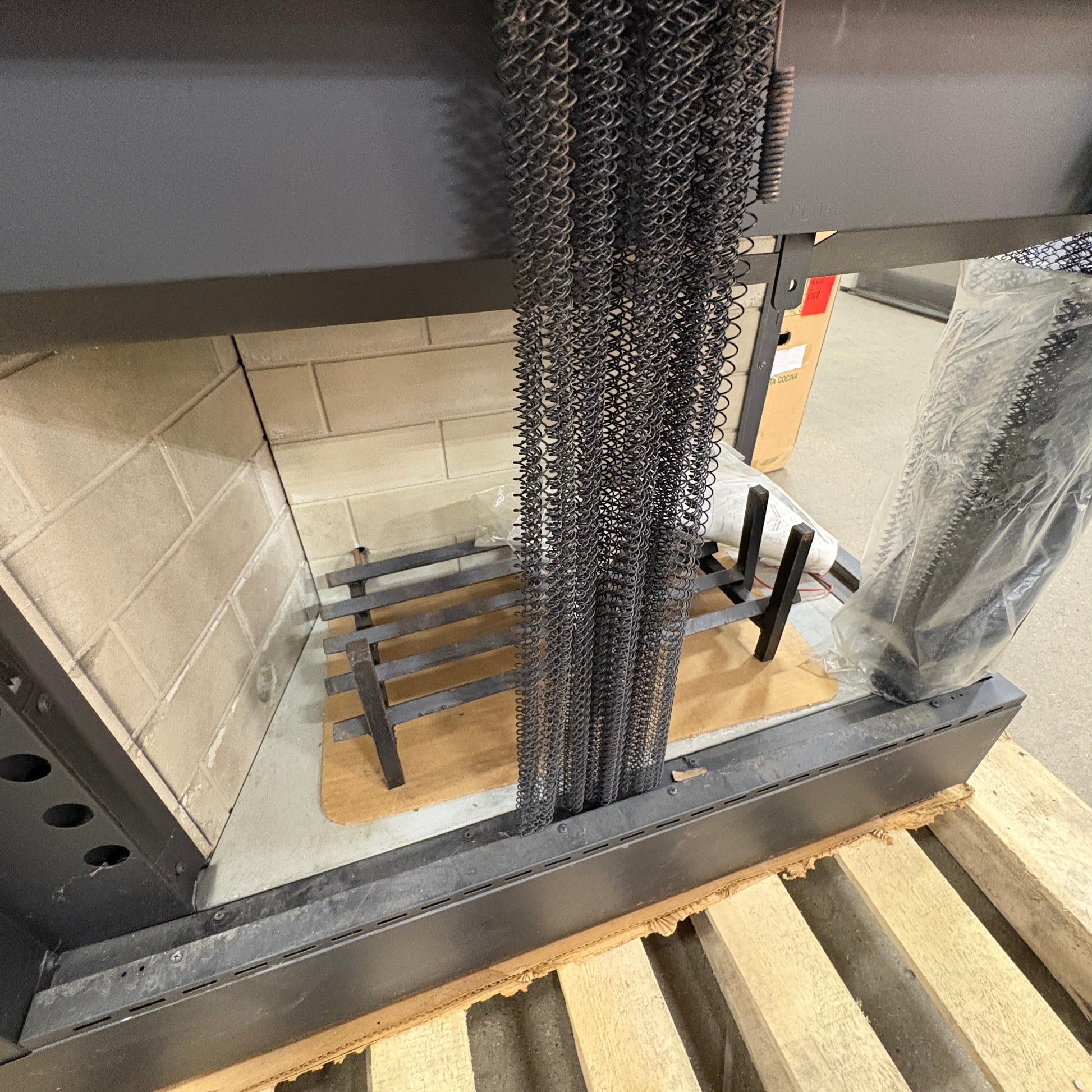 GDM Habitat for Humanity ReStore fireplace insert with black metal mesh screen and iron grate on a wooden pallet