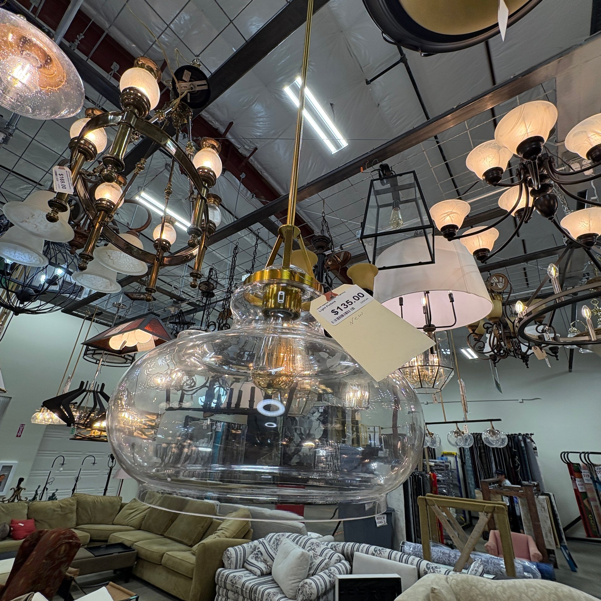 GDM Habitat for Humanity ReStore modern clear glass globe pendant light with gold-tone hardware in a retail showroom.