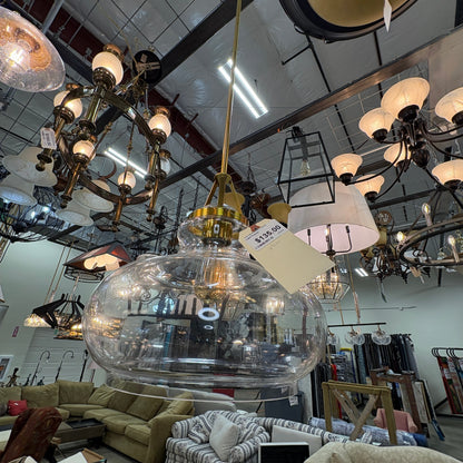 GDM Habitat for Humanity ReStore modern clear glass globe pendant light with gold-tone hardware in a retail showroom.