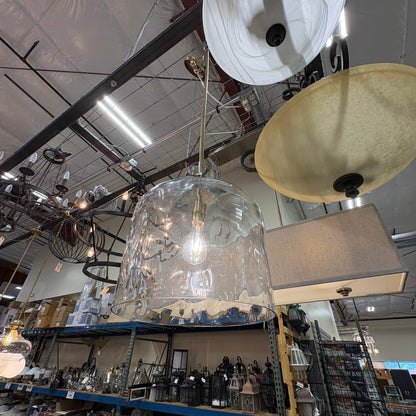 GDM Habitat for Humanity ReStore clear glass bell-shaped pendant light with brass hardware hanging in a warehouse