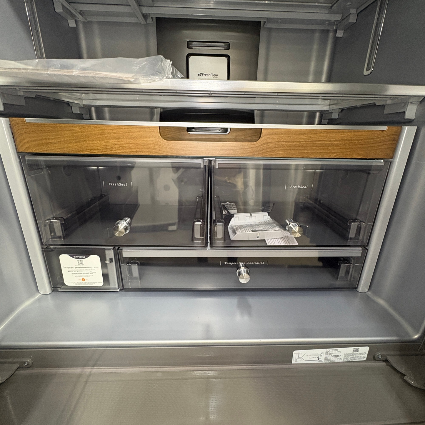 Interior of a GDM Habitat for Humanity ReStore KitchenAid French door fridge featuring wood trim and clear drawers.