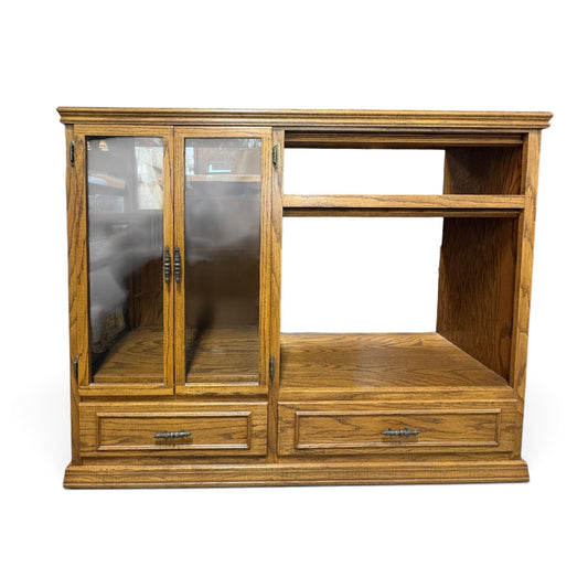 GDM Habitat for Humanity ReStore golden oak entertainment center with smoked glass doors and two bottom drawers.