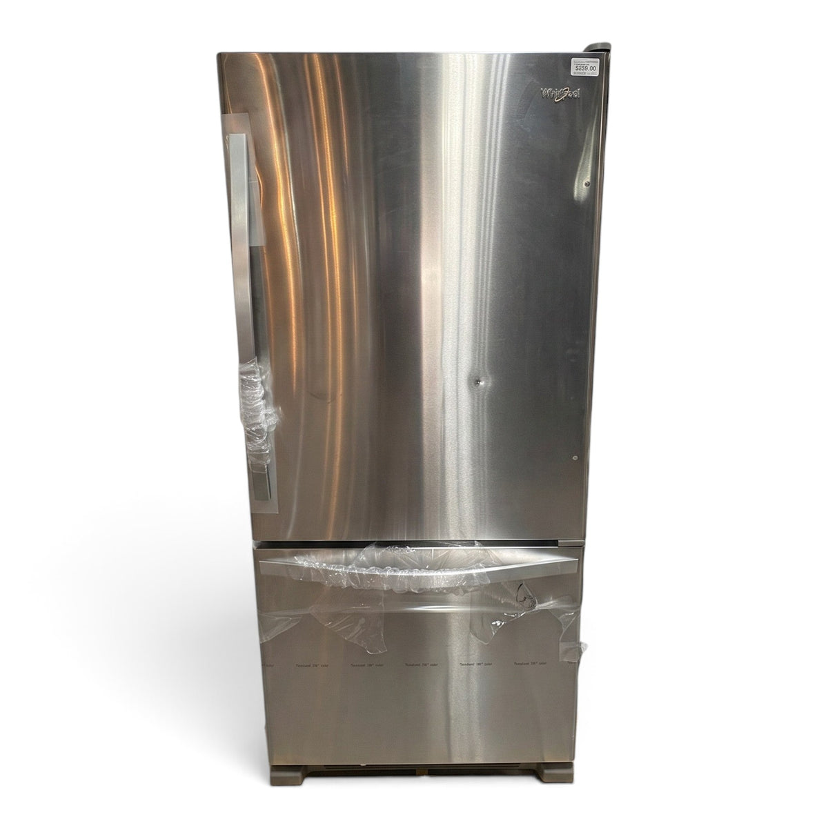 GDM Habitat for Humanity ReStore stainless steel Whirlpool bottom-freezer refrigerator on a wooden shipping pallet.