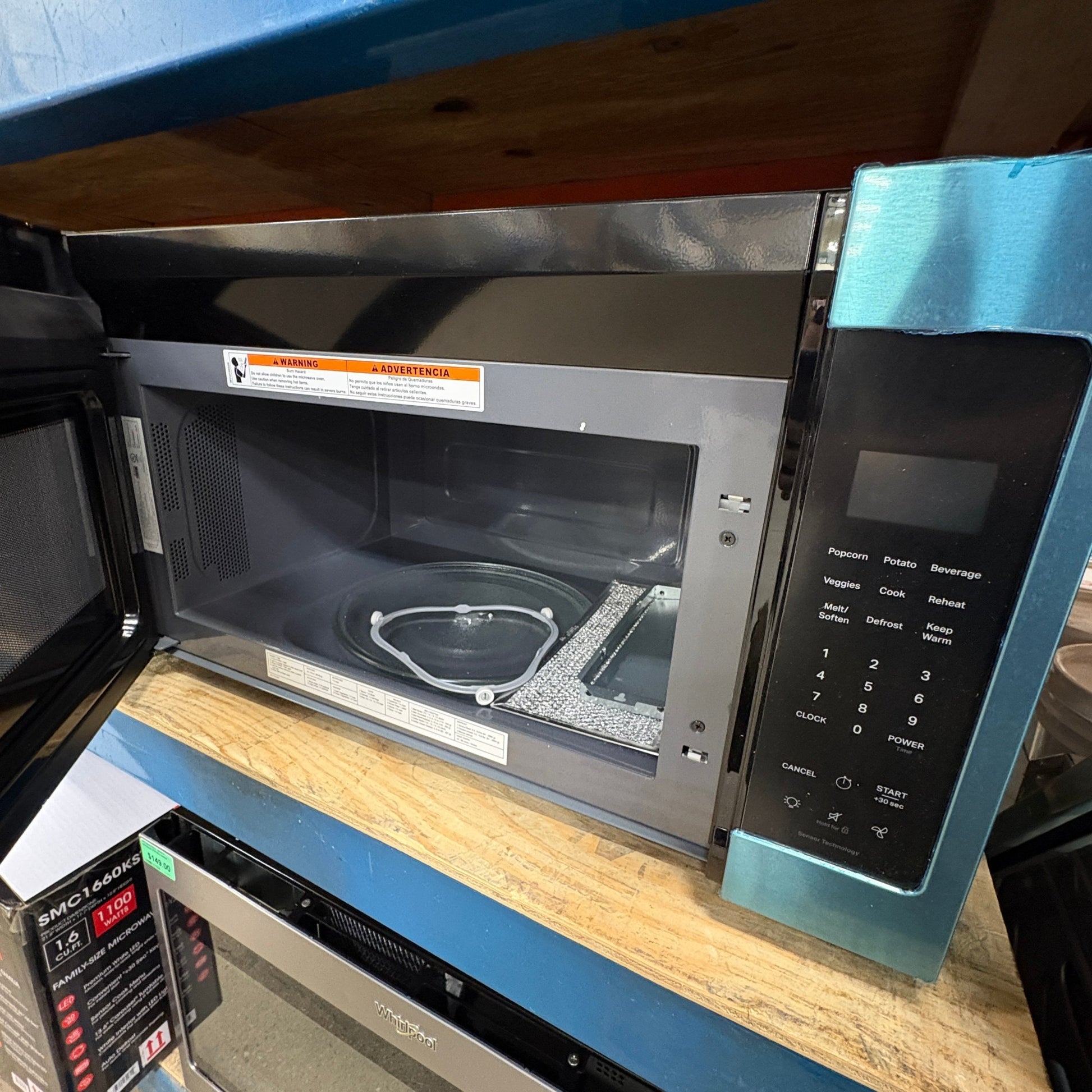 GDM Habitat for Humanity ReStore Whirlpool microwave with black finish and open door on a wooden shelf