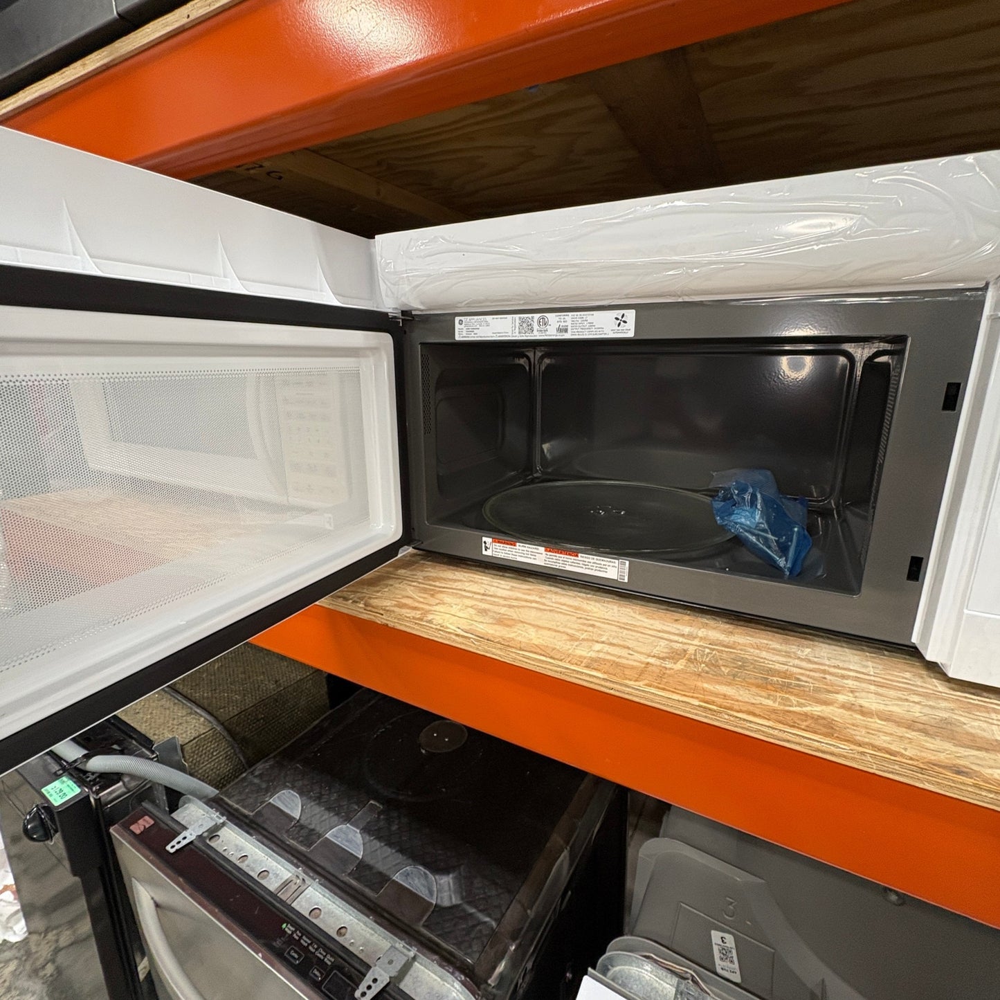 GDM Habitat for Humanity ReStore white GE over-the-range microwave oven with the door open on a warehouse shelf